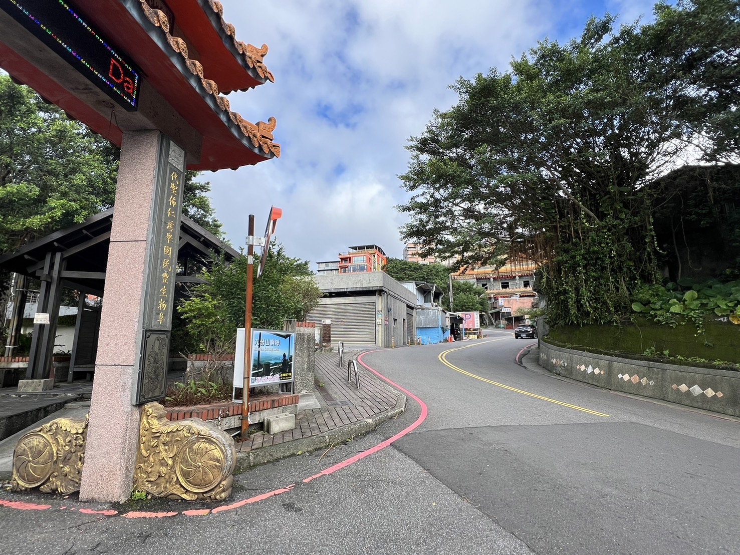 九份山嶼海民宿附近的道路轉角，通往九份老街的路線標誌清晰，背景山景與傳統建築相互映襯